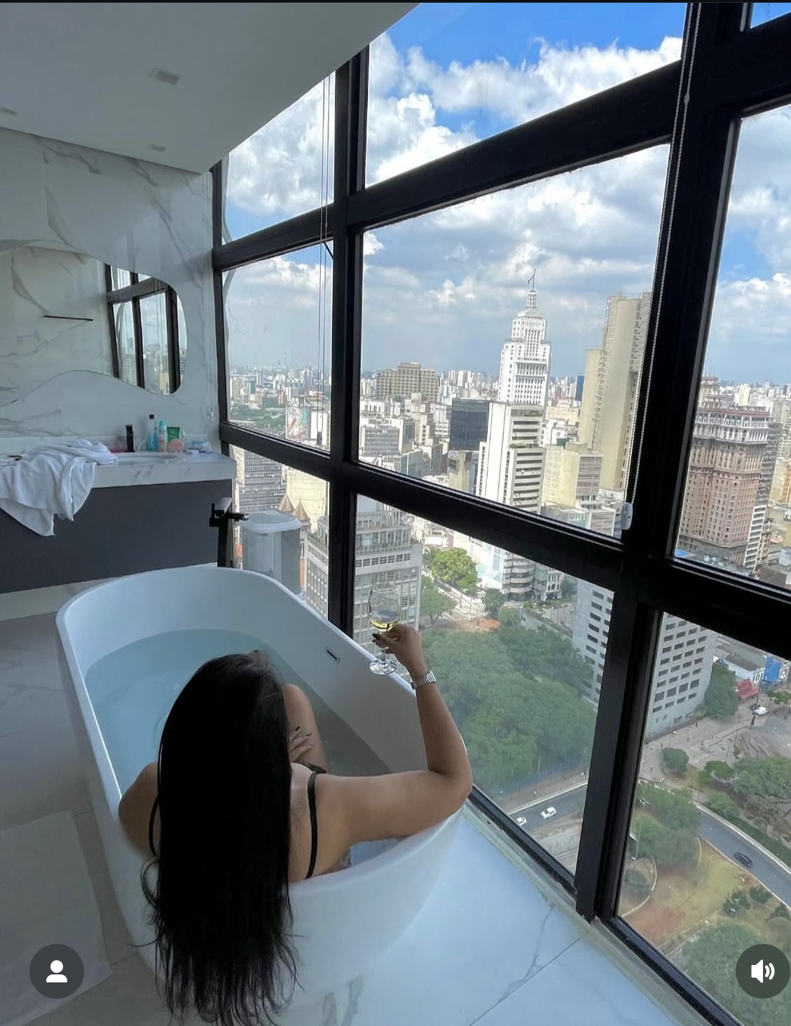 Mulher com taça de vinho na banheira olhando a vista